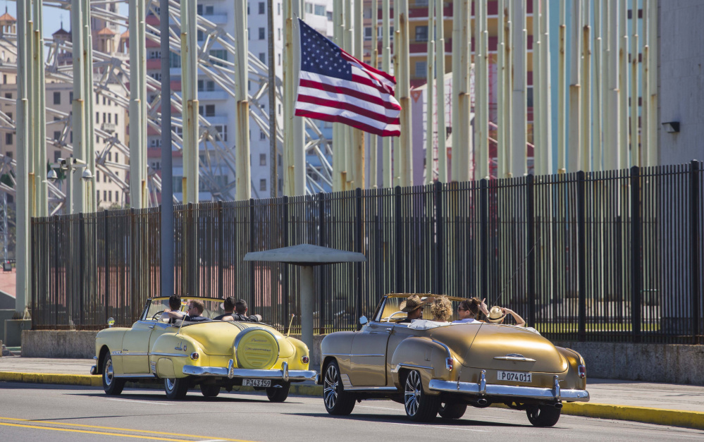 Tourists ride vintage American convertibles as they pass the U.S. embassy in Havana, Cuba, on Thursday. President Obama said that he will visit Cuba on March 21-22.