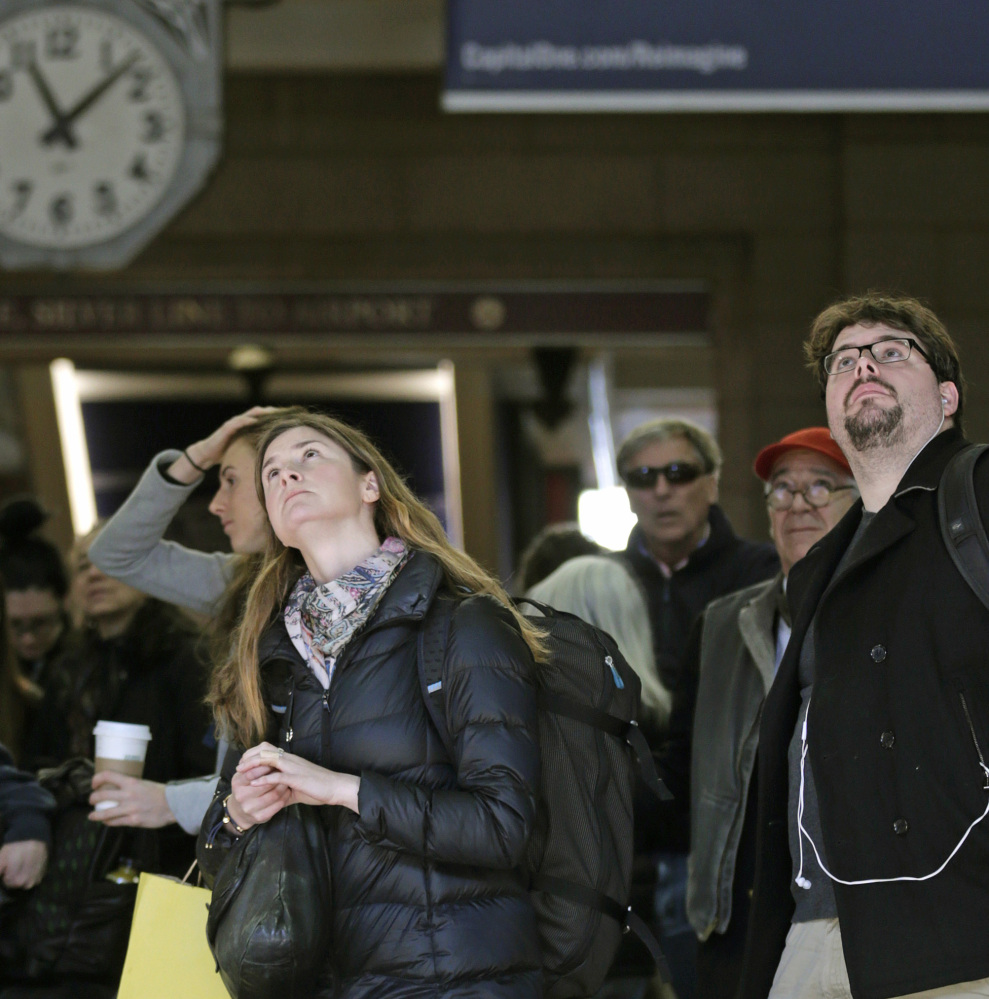 Travelers watch the train departure board at Boston’s South Station Thursday for delays and cancellations.
