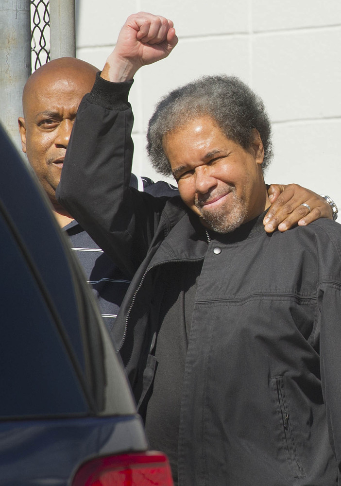 Albert Woodfox raises a clenched fist as he leaves prison with his brother.