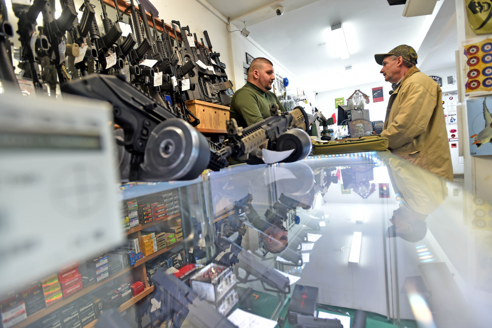 Amos Herrera, left, helps Neil Wooley of Vassalboro buy a handgun Friday at Fox Firearms Sales & Training Service in Vassalboro.