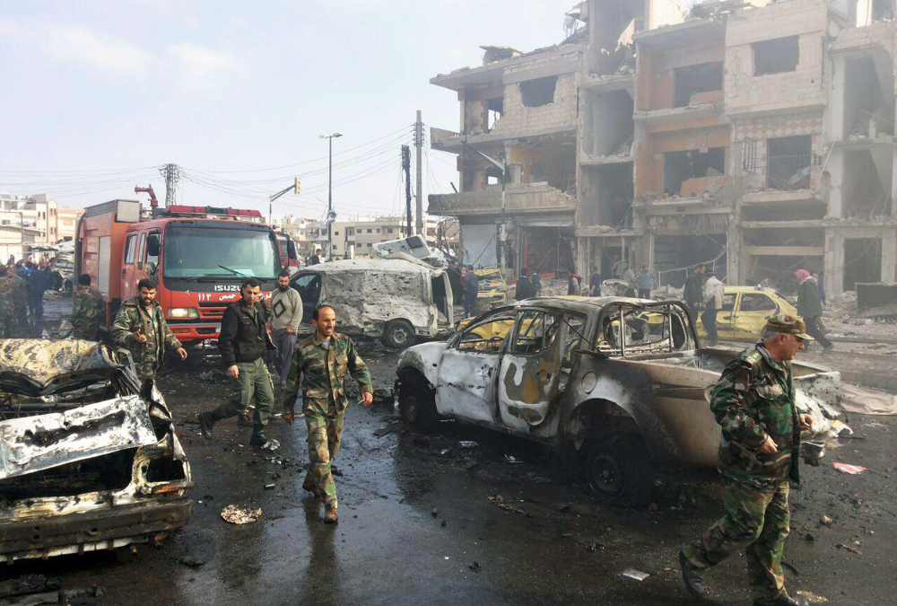 Syrian citizens gather at the scene of multiple explosions in the Sayyida Zeinab suburb outside Damascus, Syria, on Sunday.