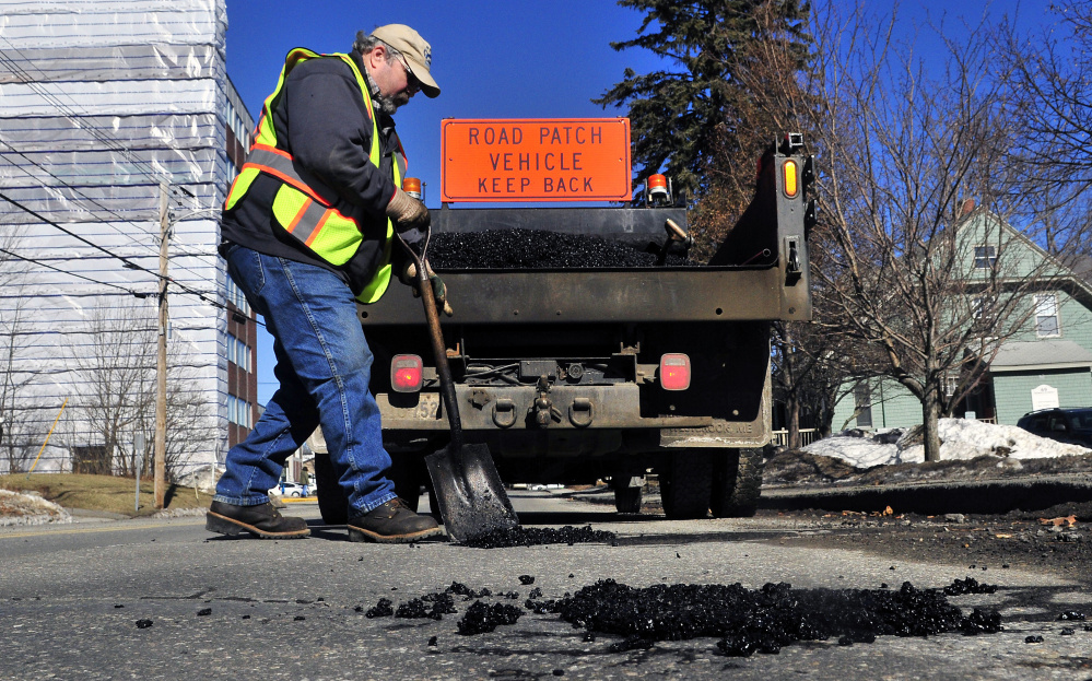 Augusta city employee Bill Jackman fills a pothole on Sewall Street in Augusta on Friday.