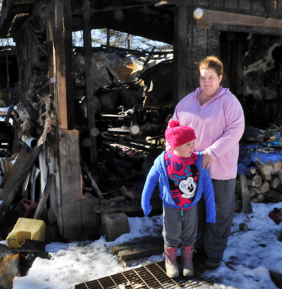 Tornia Bowring and her granddaughter, Serenity, stand outside Monday at the Norridgewock home they lived in when it was destroyed by fire last month. Tornia, and her children and husband, were subjected to a vicious social media campaign after the fire, and are now living in a camper. “I’m still grateful for all the support that people have shown ...,” she says.