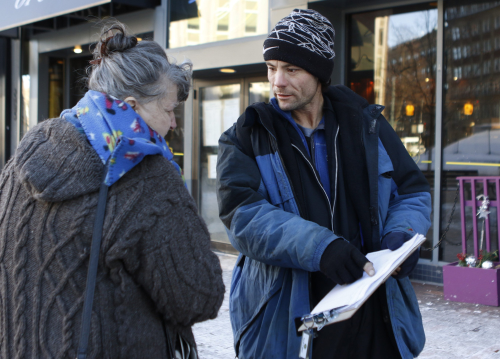 Brandon Scott, right, speaks with Joyce Lorraine as he works to collect signatures on a casino petition in Monument Square last month.