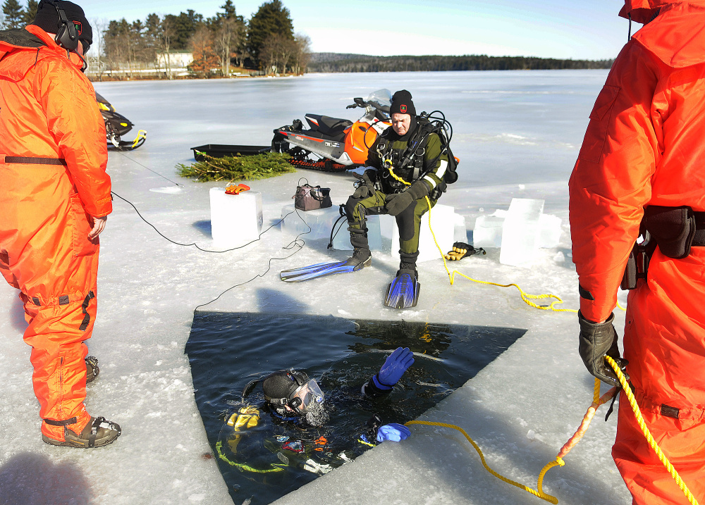 Game Warden Ethan Buuck discusses where he planned to search under the ice Monday on Salmon Lake in Belgrade with fellow members of the Maine Warden Service’s dive team.