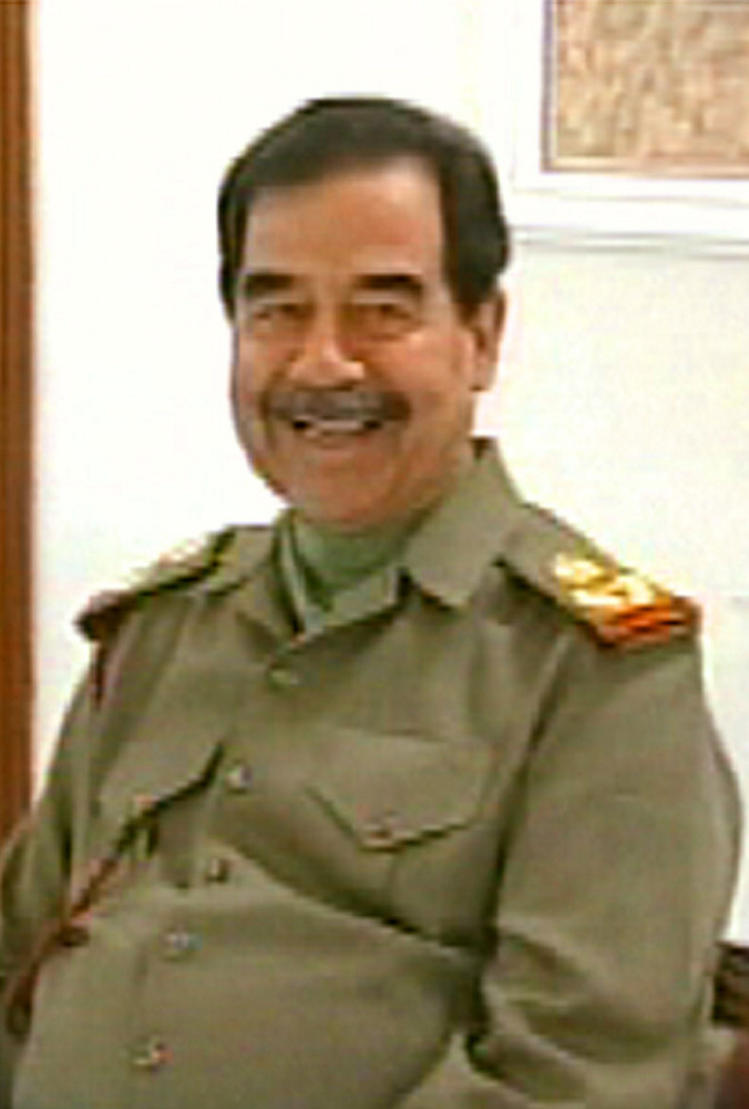 Iraqi President Saddam Hussein smiles as he talks with his son Qusai in this image broadcast on Iraqi television on Sunday, March 23, 2003. The exact date and location of the video are unknown. (AP Photo/Iraqi TV via APTN)