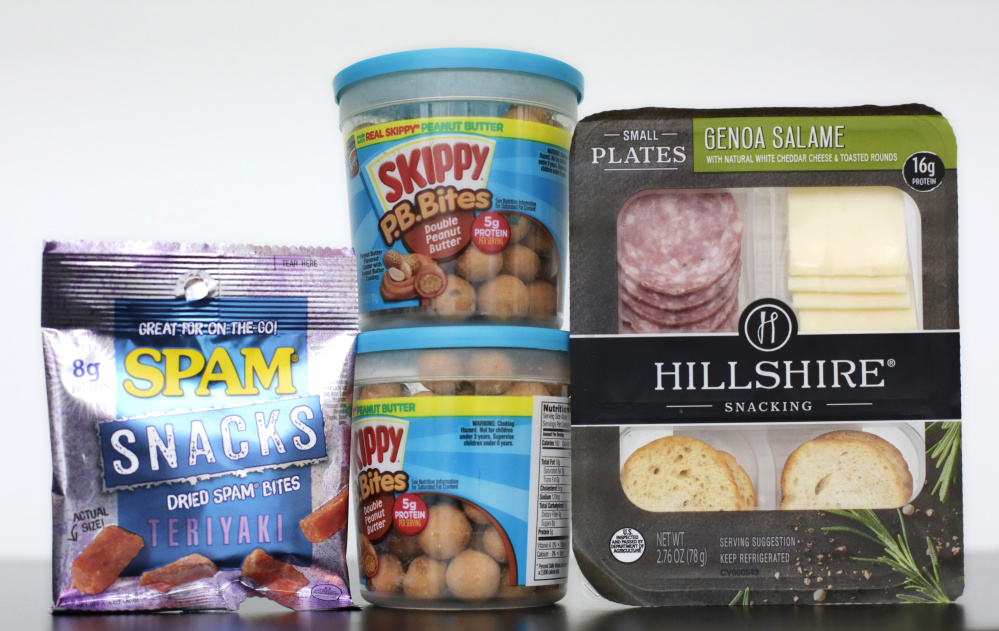 Spam Snacks, left, Skippy P.B. Bites, center, and Hillshire Genoa Salami with cheese and crackers are arranged for a photo, Wednesday, Feb. 24, 2016, in New York. As around-the-clock grazing upends the way people eat, companies are reimagining foods that aren’t normally seen as snacks to elbow in on the trend. That means everything including grilled chicken, cereal, chocolate, peanut butter and Spam are now being marketed as snacks. (AP Photo/Mark Lennihan)