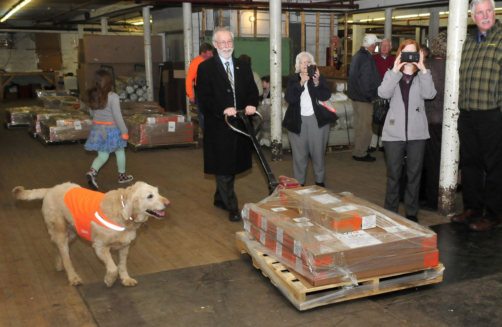 The Swains’ dog, Max smartly models a vest Wednesday while state Sen. Rod Whittemore helps load pallets of Dog Not Gone Visibility Products on an Arkansas-bound truck.