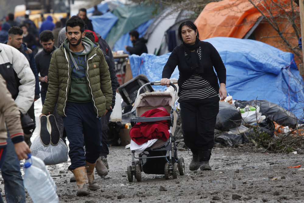 A migrant family walks in the mud at a makeshift camp in Grand-Synthe, near the town of Dunkerque, France, Wednesday.  More than 1,000 migrants live at the camp.