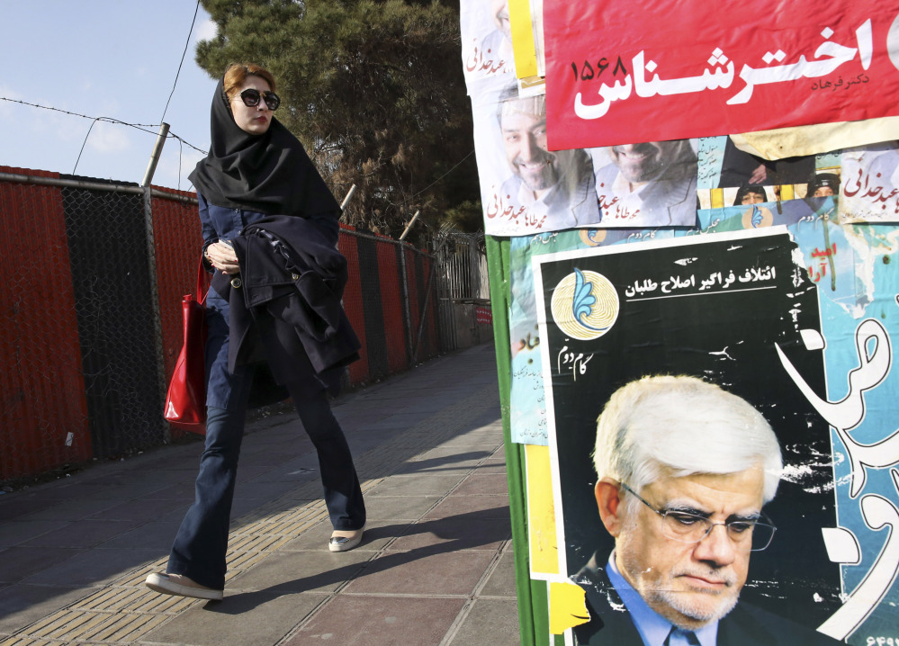 An Iranian woman walks past posters of candidates in Tehran on Thursday. Some 6,200 people are running for 290 seats in the nation’s parliament, or Majles.