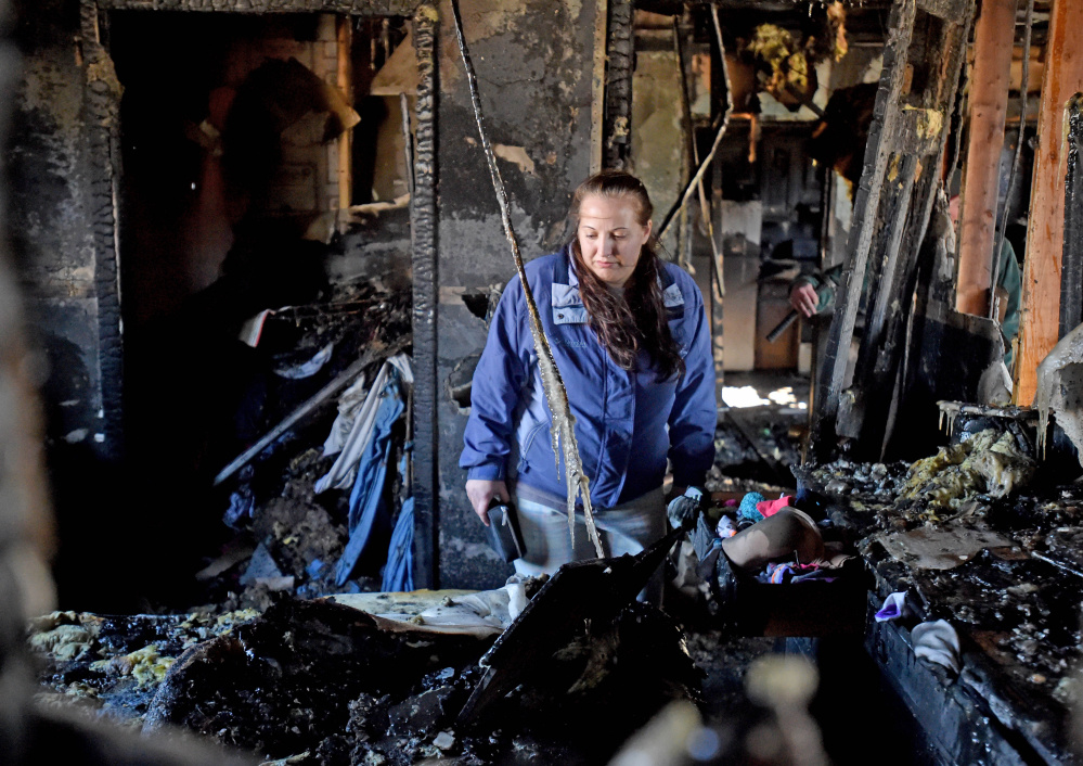 Hillary Barney, 24, looks through her belongings in her bedroom after a fire destroyed the apartment building where she lived in Cornville on Friday.