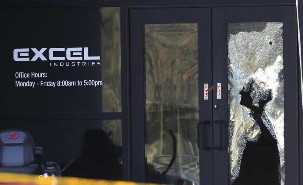 Shattered glass and bullet holes are seen at the front door of Excel Industries in Hesston, Kan., on Friday, a day after Cedric Ford stormed into the factory where he worked and shot several people.