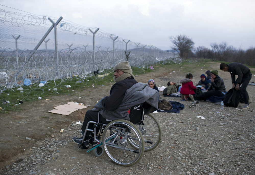 A stranded Syrian refugee on a wheelchair looks at the wire fence that separates Greece from Macedonia. Some European Union countries are taking unilateral action to shut down their borders to stem the flow of migrants.
