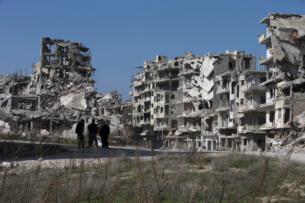 Syrian men walk through a devastated part of the old city of Homs, Syria.