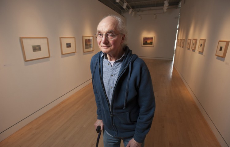 UMaine art instructor Michael Lewis poses for a portrait at Lord Hall Gallery, where 52 pieces of his art hang. 
Kevin Bennett/Staff Photographer