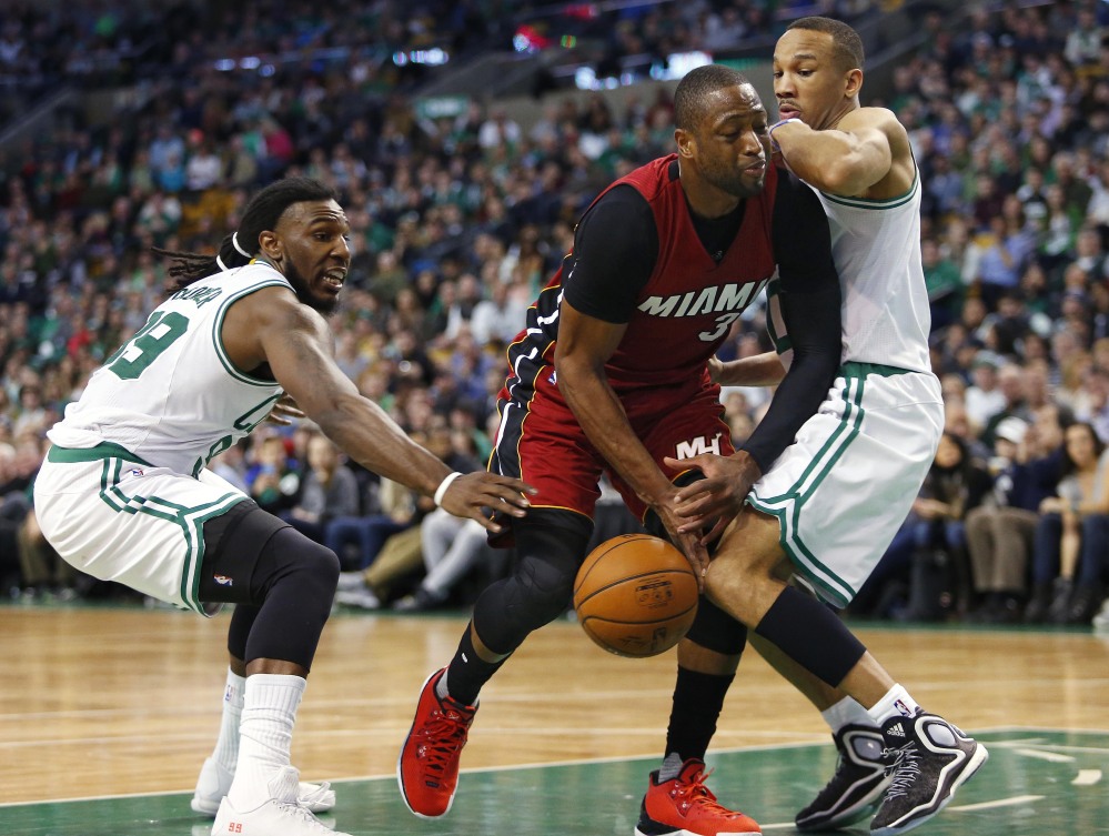 Miami’s Dwyane Wade loses the ball while trying to cut between Boston’s Jae Crowder, left, and Avery Bradley during the second half of the Celtics’ 101-89 win Saturday in Boston.