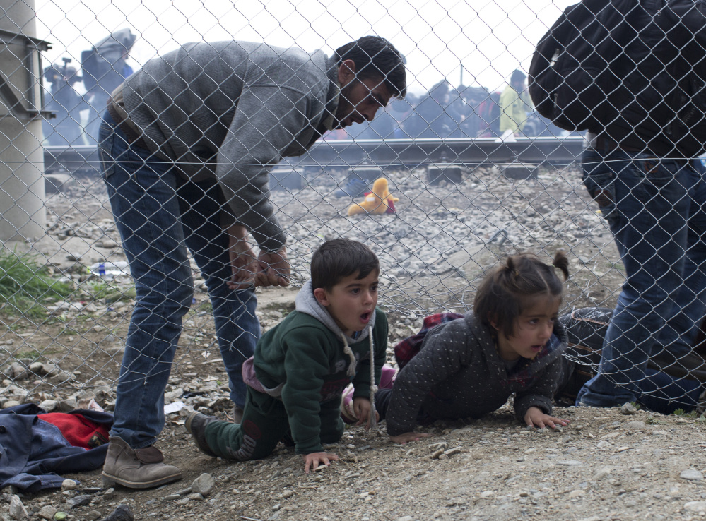 A man helps children to run away after Macedonian police fired tear gas at a group of the refugees and migrants who tried to push their way into Macedonia, breaking down a border gate near the northern Greek village of Idomeni on Monday.