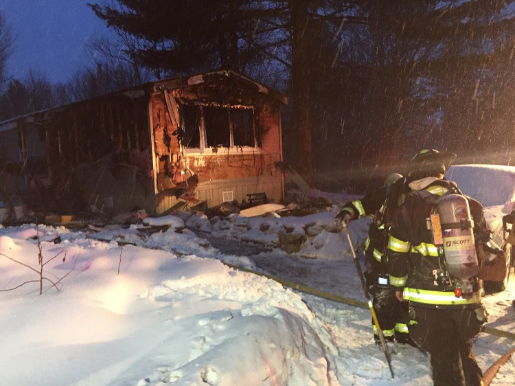 Firefighters work at the scene of Monday's fire on a private road off Snow Hill Road in New Gloucester.