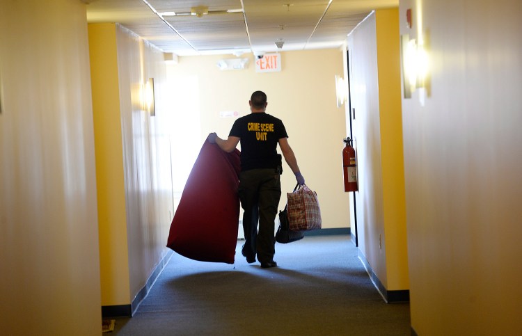 A Portland police investigator carries items down a hallway Wednesday at 88 Gilman St. from the apartment where last week's shooting killed a 36-year-old man.
Shawn Patrick Ouellette/Staff Photographer