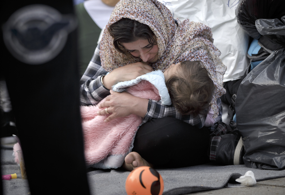 A migrant woman cries while holding a baby in Athens on Monday. Border restrictions farther north in the Balkans have left thousands of refugees stranded in Greece.