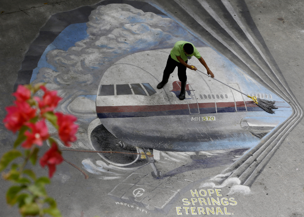 2014 Associated Press File Photo A school utility worker mops a mural depicting the missing Malaysia Airlines Flight 370 at the Benigno “Ninoy” Aquino High School campus at Makati city east of Manila, Philippines.