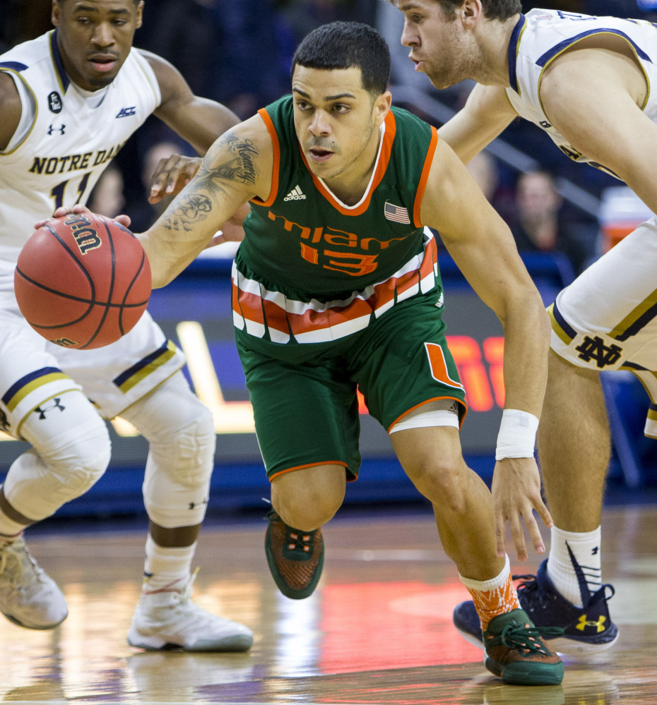 Miami’s Angel Rodriguez drives between Notre Dame’s Demetrius Jackson, left, and A.J. Burgett  during the first half Wednesday night. Rodriguez had 19 points in Miami’s 68-50 road win.