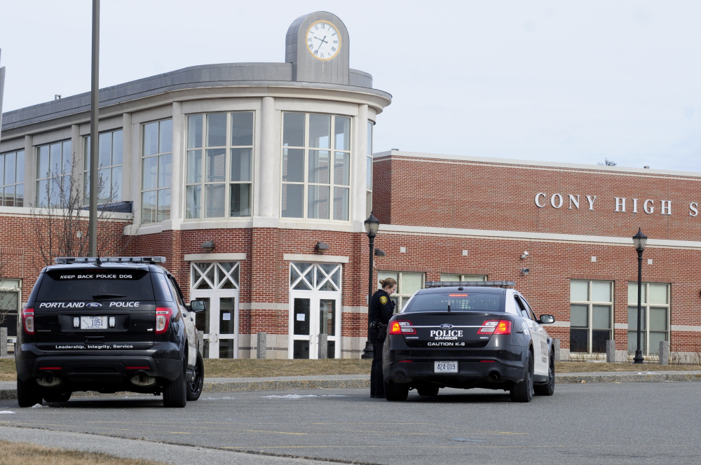 An Augusta police officer confers with officers from Bangor and Portland in front of Cony High School in Augusta after a bomb threat was emailed in to the school.