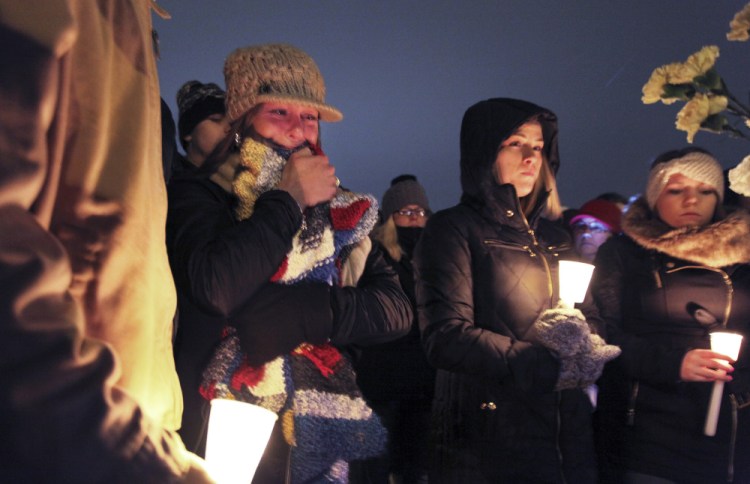 A woman hugs a prayer shawl as it gets passed through the crowd of more than 100 people at Friday night’s vigil for missing Maine Maritime Academy student David Breunig.