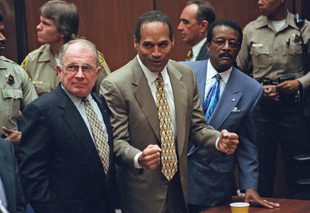 O.J. Simpson, center, reacts as he is found not guilty of murdering his ex-wife Nicole Brown and her friend Ron Goldman, with members of his defense team, F. Lee Bailey, left, and Johnnie Cochran Jr., right, in 1995 in court in Los Angeles. 