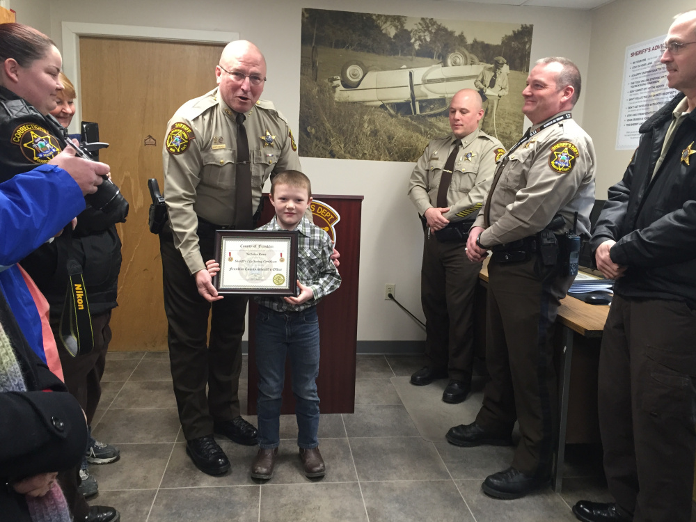 Franklin County Sheriff Scott Nichols gives Nicholas Rowe, 9, a Life Saving Certificate on Friday for his role in helping save the life of trucker Charles Bolduc in December.