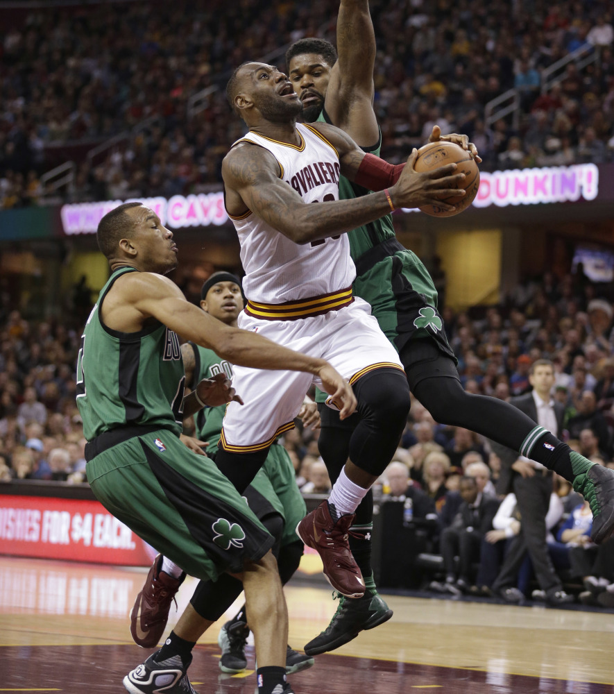 Cleveland’s LeBron James, center, drives to the basket against Boston’s Avery Bradley, left, and Amir Johnson during the Cavaliers’ 120-103 win Saturday in Cleveland.