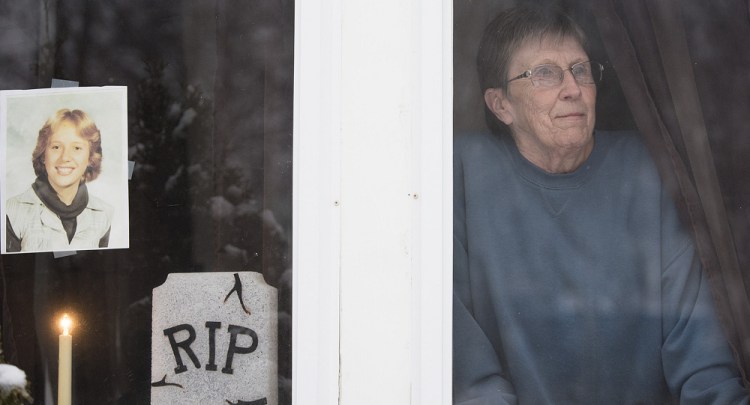 Pam McLain looks out the front porch window of her home in East Millinocket, where a candle has been burning for her murdered daughter, Joyce, since 1980. Kevin Bennett
