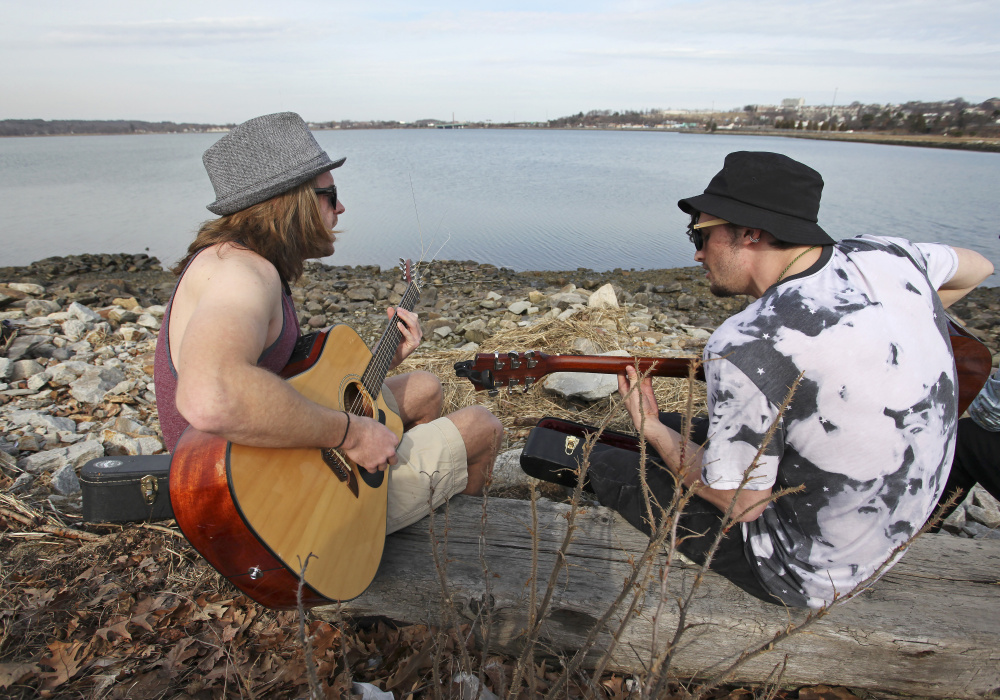P.J. Moon of North Carolina and Ollie Hewat of Colorado, who are both currently living in Portland, enjoy the view along Back Cove and the mild temperatures Wednesday while they practice songs for their new band.