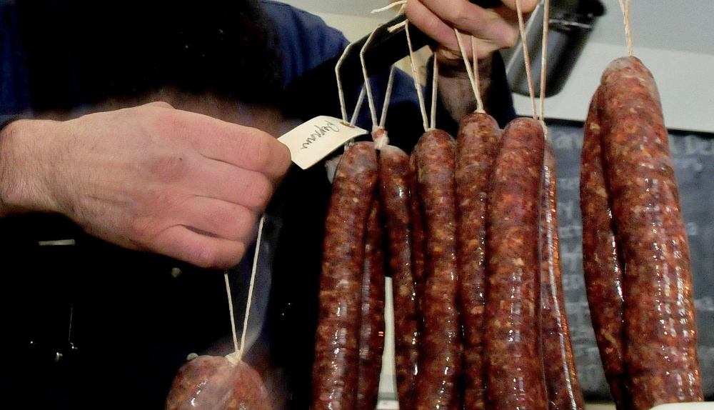 Matthew Secich hangs sausages on a bar to dry at his Charcuterie shop in Unity on Wednesday.