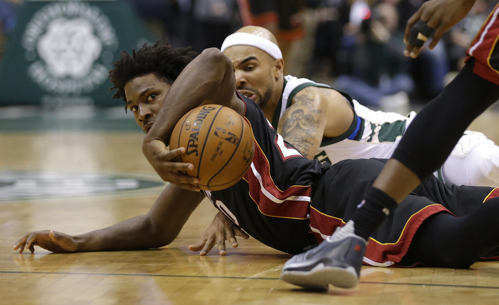 Justise Winslow of the Miami Heat, foreground, and Jerryd Bayless of the Milwaukee Bucks scramble for a loose ball Wednesday night during the first half of Milwaukee’s 114-108 victory at home.
