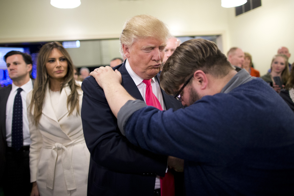 After a Sunday service in Council Bluffs, Iowa, this winter, Pastor Joshua Nink, right, prays for Republican presidential candidate Donald Trump as Trump’s wife, Melania, watches.