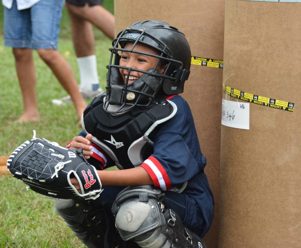 Many of the kids in Honduras were afraid to put on the equipment and catch, but this young boy was excited and had a great time – in front of a makeshift backstop of shipping barrels.