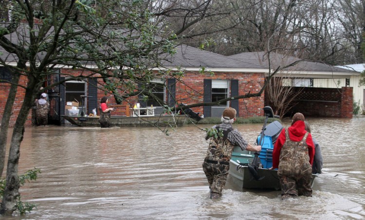 Volunteers return to a flooded house in Clarksdale, Miss., Friday, to assist the owners retrieve personal items as floodwaters continued to rise after another morning of rain.