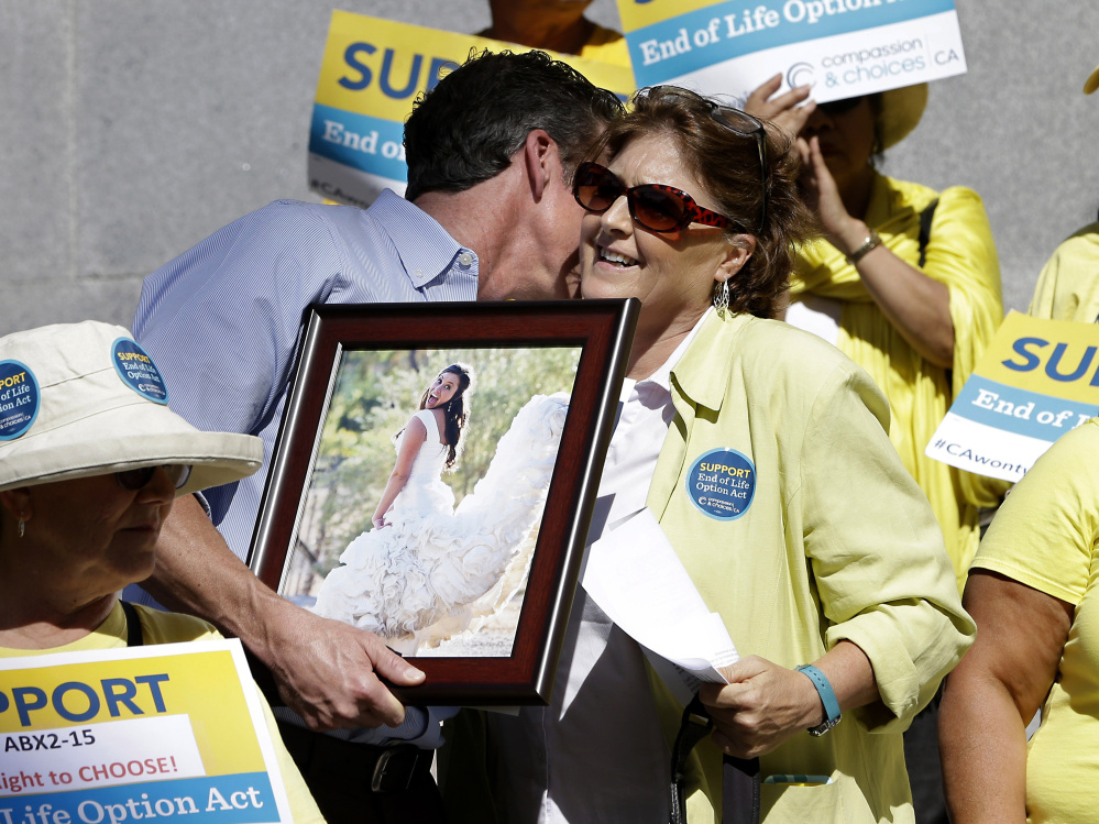 Elizabeth Wallner, who is dying of colon cancer, is hugged by Dan Diaz after she spoke at a rally calling for California Gov. Jerry Brown to sign the right-to-die legislation Sept. 24 at the Capitol in Sacramento. Diaz is holding a photo of his late wife, Brittany Maynard, the 29-year-old California woman with brain cancer who moved to Oregon to legally end her life. The measure’s implementation was delayed in California and will go into effect in June of this year.