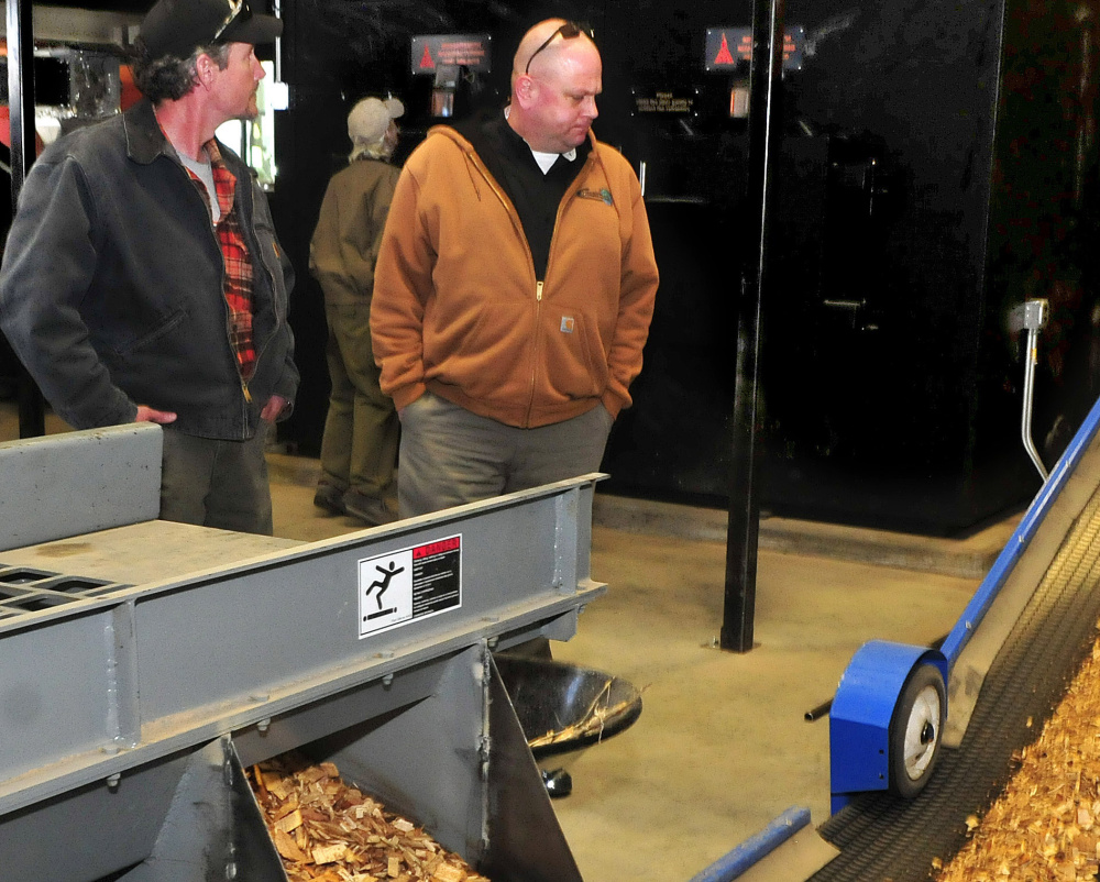Doug Dubord, left, and Jon Baker watch as wood chips move on a conveyor into the biomass boiler at the University of Maine Farmington on Sunday.