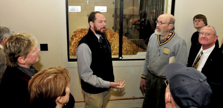Outside a wood chip storage room, University of Maine Farmington Director of Facilities Jeff McKay, left, explains the process of using wood chips to produce energy to Tom Bissell and others on a tour of the UMF Central Heating Plant on Sunday.