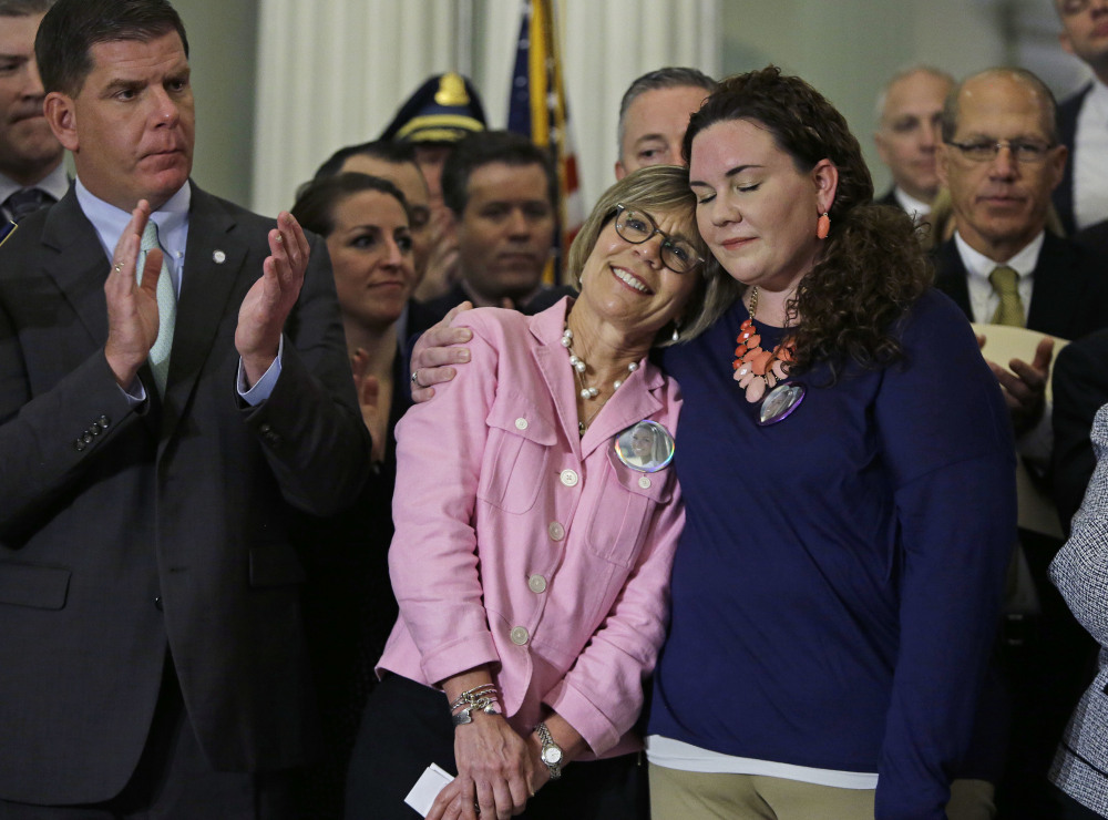 Janice McGrory of Harwich, who lost her daughter, Liz, to a heroin overdose in 2011, is hugged by her other daughter, Amy, after she spoke during a signing ceremony at the Statehouse Monday in Boston. Mass.