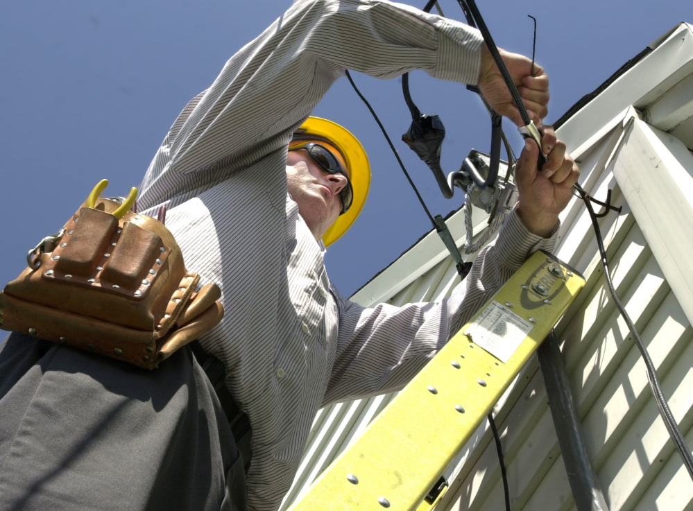 Dave Jackson works on a home cable service installation. Some cannot afford Internet access without the help of subsidies.