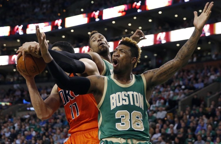 The Celtics’ Marcus Smart grimaces as Oklahoma City’s Enes Kanter grabs a rebound in the second quarter of Wednesday night’s game in Boston.