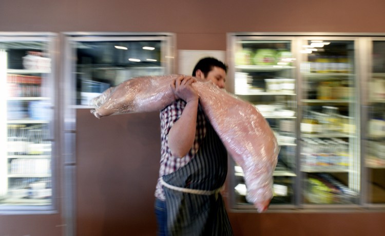 Pete Sueltenfuss carries a pig from the cooler at Otherside Delicatessen.