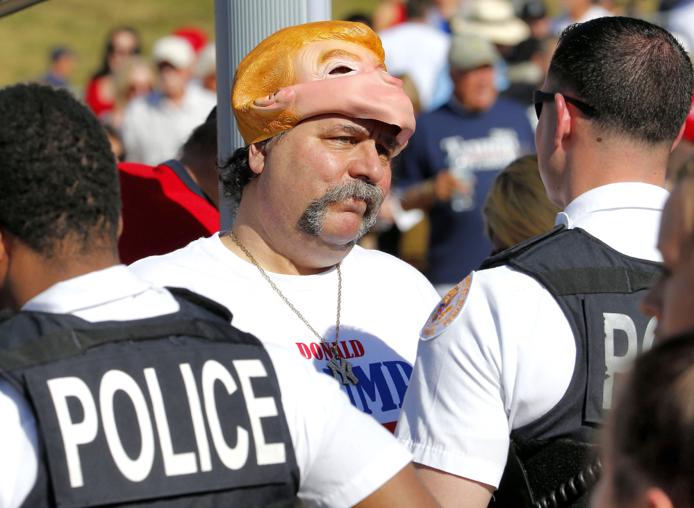 A supporter is told by police he can’t wear his Trump face mask before a campaign rally with Republican presidential candidate Donald Trump Saturday in Fountain Hills, Ariz.