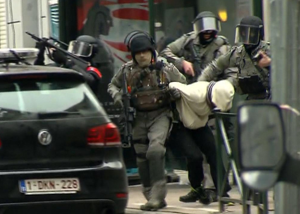 In this framegrab taken from VTM, armed police officers escort a suspect to a police vehicle during a raid in the Molenbeek neighborhood of Brussels, Belgium, Friday March 18, 2016. After an intense four-month manhunt across Europe and beyond, police on Friday captured Salah Abdeslam, the top fugitive in the Paris attacks in the same Brussels neighborhood where he grew up. (VTM via AP) BELGIUM OUT