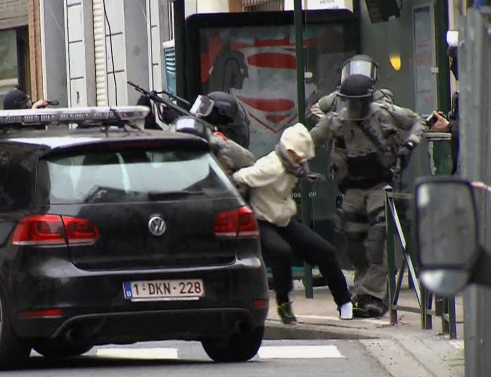 In this framegrab taken from VTM, something appears to drop from inside the trouser leg of Salah Abdeslam, centre, as he is arrested by police and bundled into a police vehicle during a raid in the Molenbeek neighborhood of Brussels, Belgium, Friday March 18, 2016.  After an intense four-month manhunt across Europe and beyond, police on Friday captured Salah Abdeslam, the top suspect in last year's deadly Paris attacks, in the same Brussels neighborhood where he grew up. (VTM via AP) BELGIUM OUT