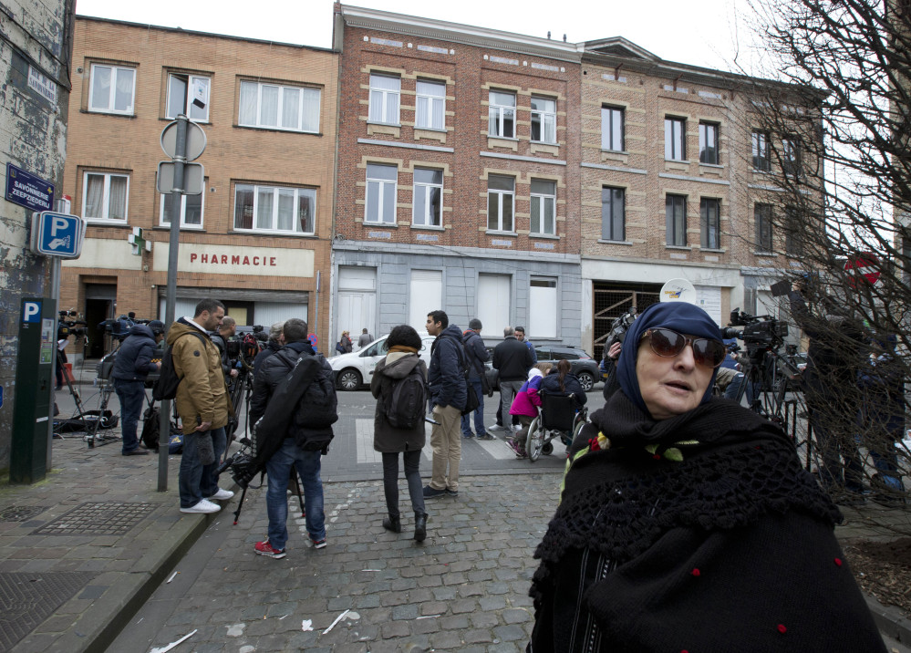 A woman passes the house, center rear, where Europe’s No. 1 fugitive Salah Abdeslam was arrested Friday after a four-month manhunt in the Molenbeek neighborhood of Brussels, Belgium.