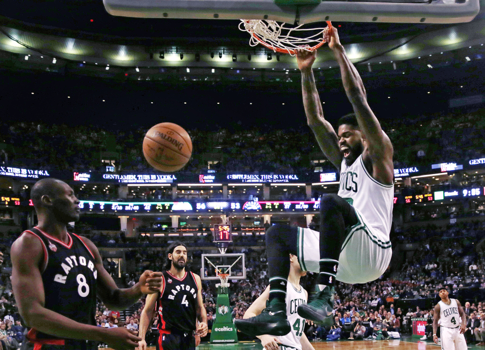 Celtics forward Amir Johnson hangs on the rim on a slam dunk against the Raptors in Wednesday night’s game at Boston. The Celtics won, 91-79.